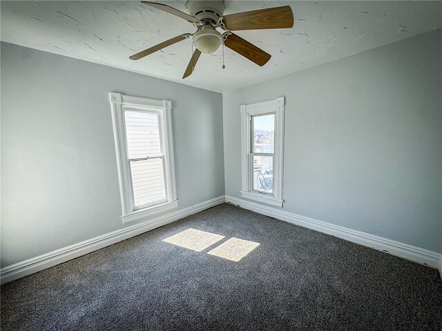 carpeted empty room featuring baseboards, a wealth of natural light, and ceiling fan