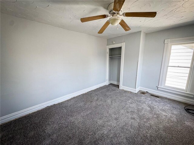 unfurnished bedroom featuring visible vents, baseboards, carpet flooring, a closet, and a ceiling fan