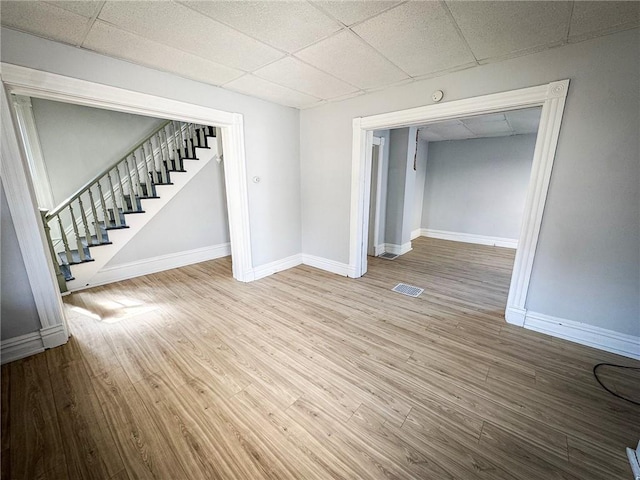 spare room featuring visible vents, a paneled ceiling, wood finished floors, and stairs