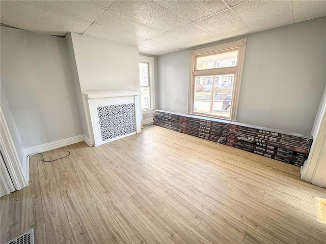 interior space featuring visible vents, wood finished floors, baseboards, a fireplace, and a paneled ceiling