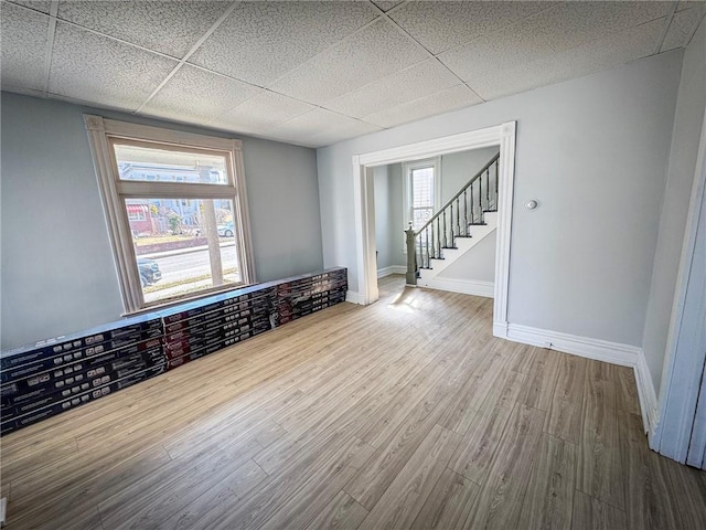 spare room with a wealth of natural light, a paneled ceiling, baseboards, and wood finished floors