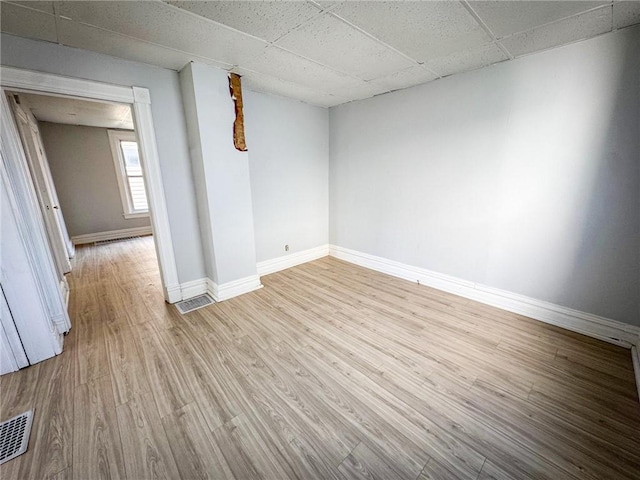 spare room with visible vents, a paneled ceiling, baseboards, and wood finished floors