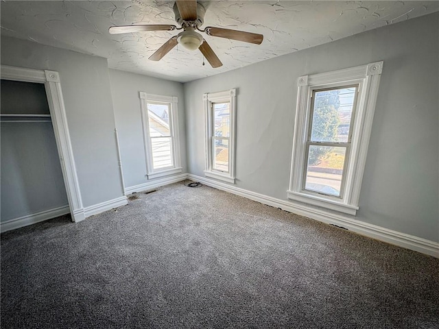 unfurnished bedroom featuring ceiling fan, a textured ceiling, baseboards, and carpet floors