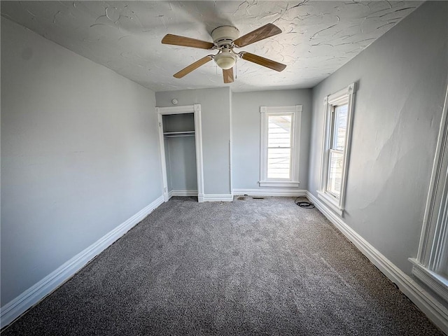 unfurnished bedroom featuring a ceiling fan, baseboards, a closet, a textured ceiling, and carpet flooring