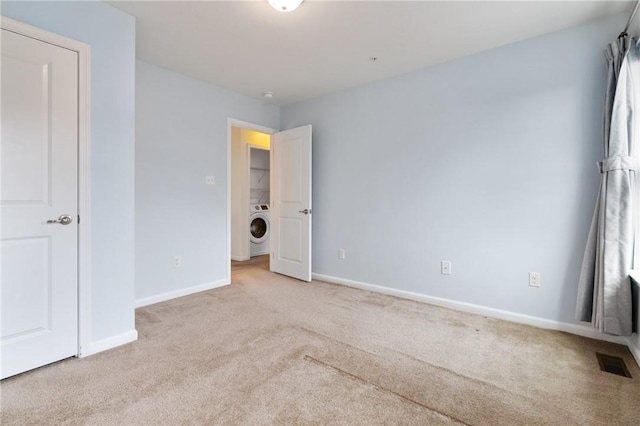 unfurnished bedroom with baseboards, visible vents, washer / clothes dryer, and carpet floors