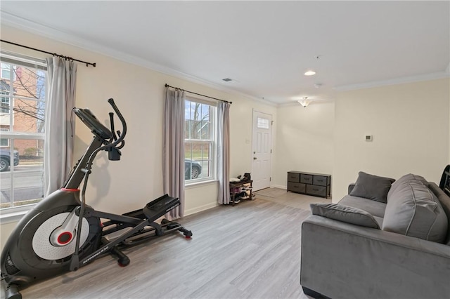 exercise area featuring visible vents, baseboards, ornamental molding, and light wood finished floors