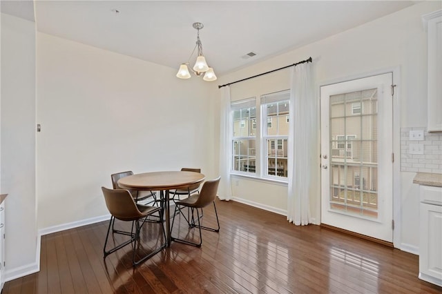 dining room with dark wood finished floors, a notable chandelier, visible vents, and baseboards