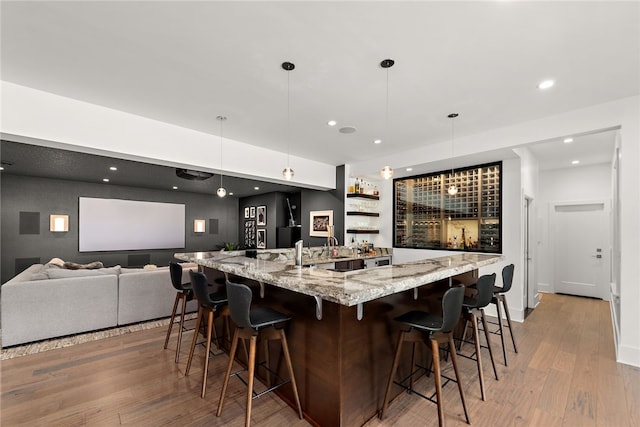 bar with baseboards, pendant lighting, recessed lighting, wet bar, and light wood-style floors