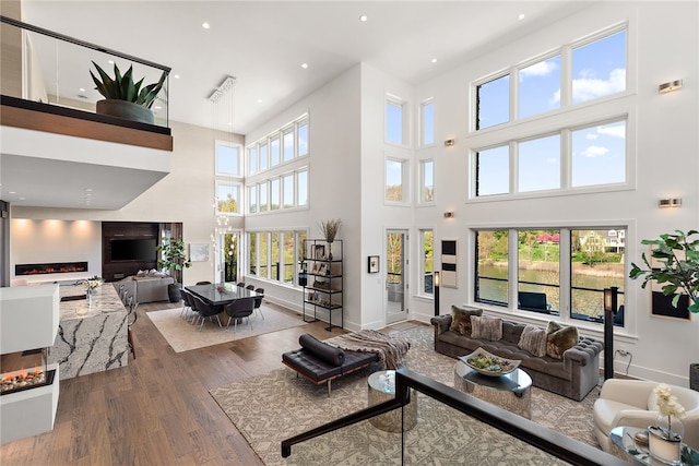 living room featuring recessed lighting, baseboards, a lit fireplace, and wood finished floors