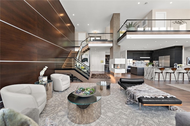 living area featuring stairway, recessed lighting, wood finished floors, and a high ceiling