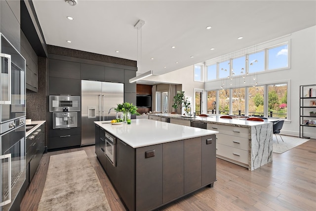 kitchen with a spacious island, built in refrigerator, light wood-type flooring, light countertops, and modern cabinets