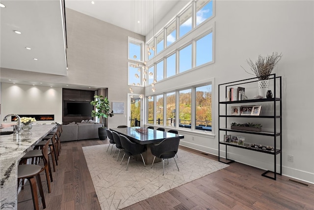 dining space with dark wood-type flooring, recessed lighting, baseboards, and a wealth of natural light