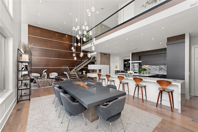 dining space featuring stairway, visible vents, a high ceiling, recessed lighting, and light wood-style floors