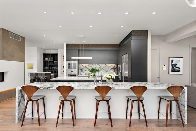 kitchen with a spacious island, modern cabinets, visible vents, and light wood-type flooring