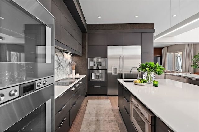 kitchen with tasteful backsplash, built in appliances, modern cabinets, and light countertops