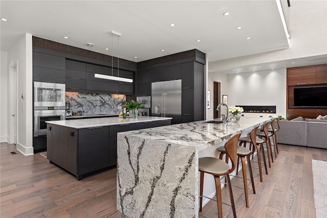 kitchen with a large island, a sink, stainless steel appliances, and modern cabinets