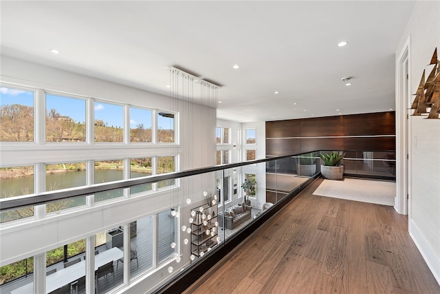 hall featuring a wealth of natural light, a water view, wood finished floors, and recessed lighting