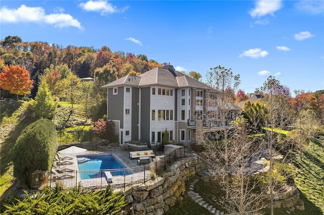 rear view of house with a patio area, a fenced in pool, and fence