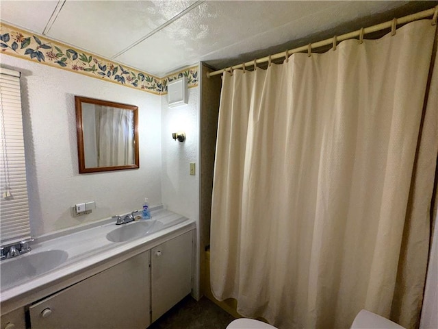 bathroom with a shower with shower curtain, double vanity, toilet, and a sink