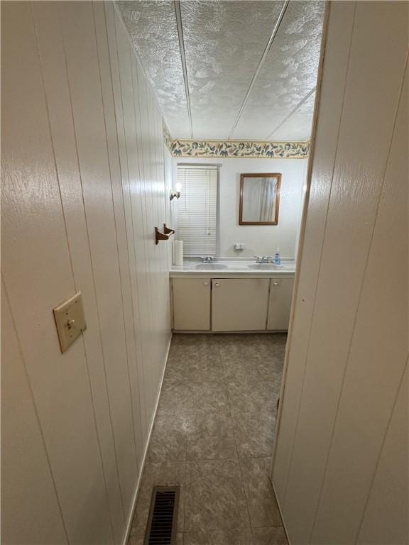 bathroom featuring visible vents, a textured ceiling, vanity, and wooden walls