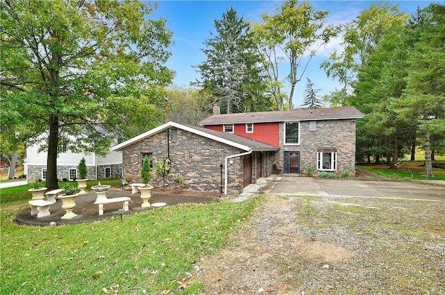 view of front of property featuring brick siding, a front yard, and dirt driveway