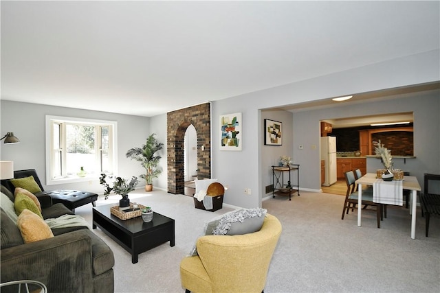 living room featuring baseboards, light carpet, and arched walkways