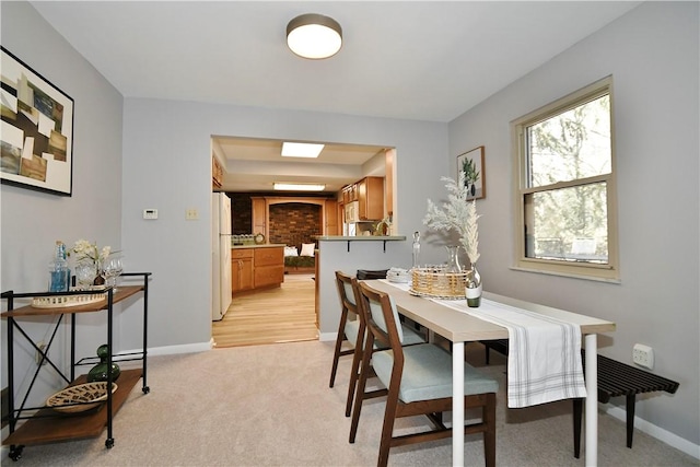 dining space featuring baseboards and light carpet