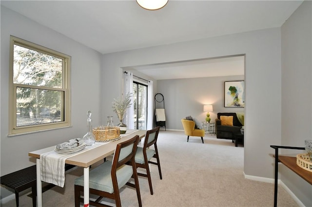 dining area featuring baseboards and light colored carpet