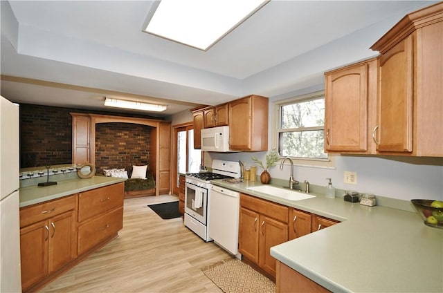 kitchen with white appliances, light countertops, light wood-type flooring, and a sink