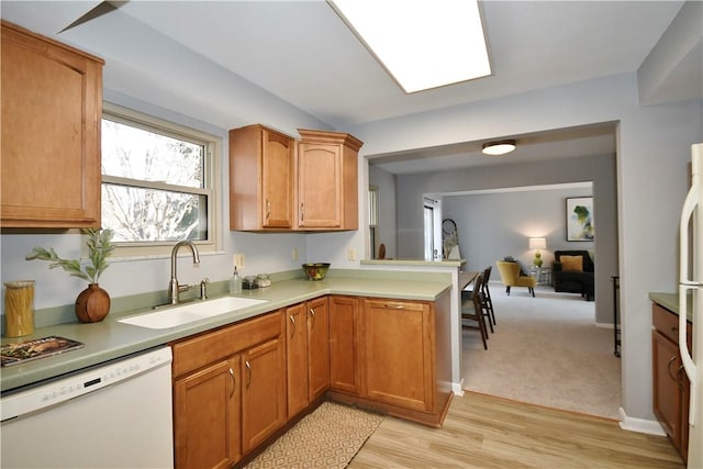 kitchen featuring white appliances, brown cabinetry, a sink, light countertops, and light wood-type flooring