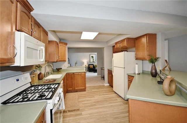 kitchen featuring white appliances, light wood finished floors, a sink, light countertops, and brown cabinets