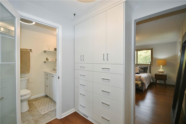 ensuite bathroom with vanity, toilet, wood finished floors, and baseboards