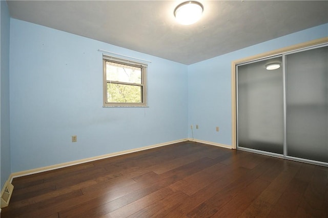 unfurnished bedroom with visible vents, dark wood-style floors, a closet, and baseboards