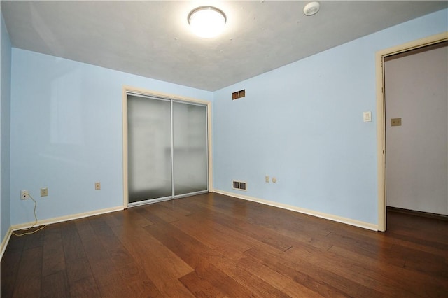 unfurnished bedroom with a closet, visible vents, baseboards, and wood-type flooring