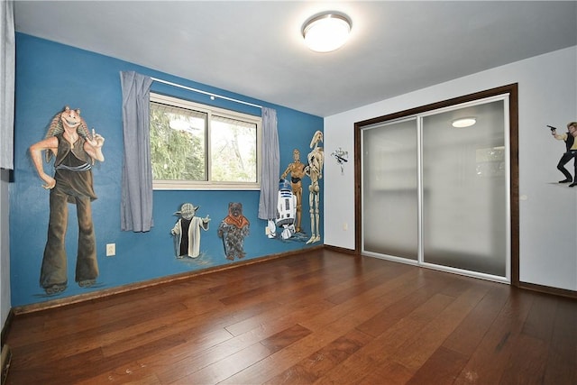 unfurnished bedroom with a closet, baseboards, and wood-type flooring