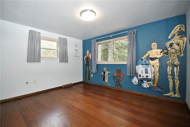 empty room featuring visible vents, baseboards, and wood-type flooring