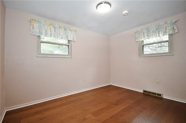 empty room featuring visible vents, baseboards, and dark wood-style flooring