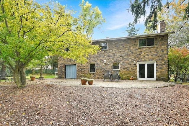 back of house with a patio area, a chimney, and brick siding