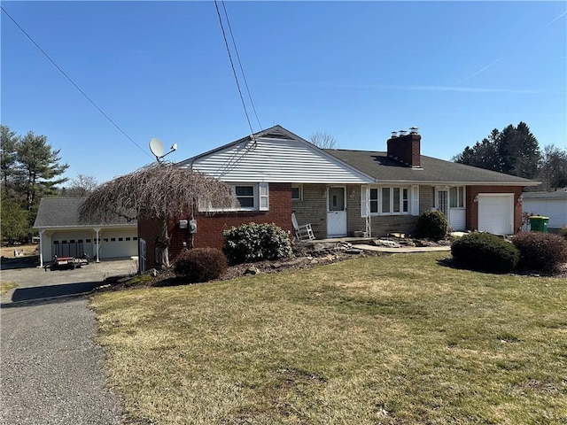 view of front of house with brick siding, a front yard, a chimney, and an attached garage