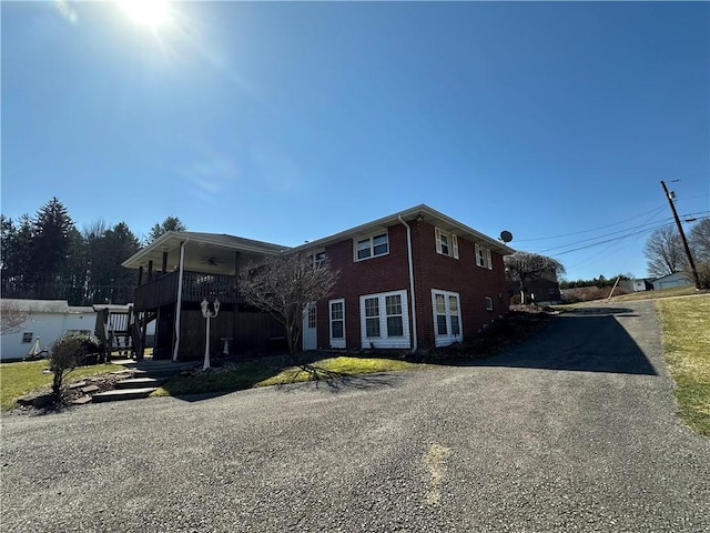 view of front of house featuring brick siding, driveway, stairs, and a ceiling fan