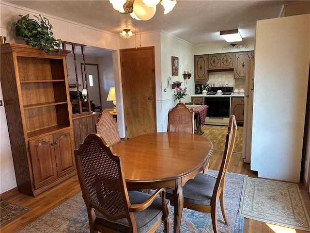 dining room with crown molding, a notable chandelier, and wood finished floors