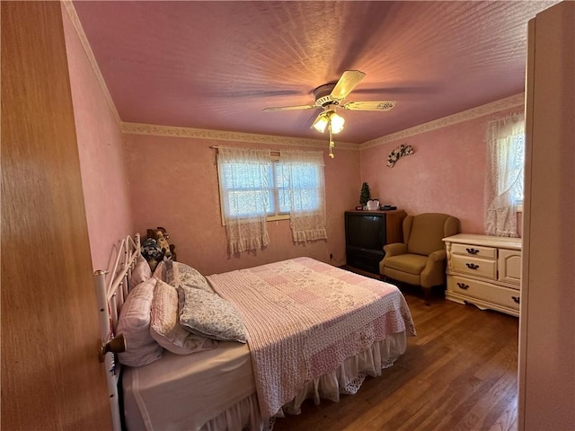 bedroom featuring a ceiling fan, crown molding, and wood finished floors