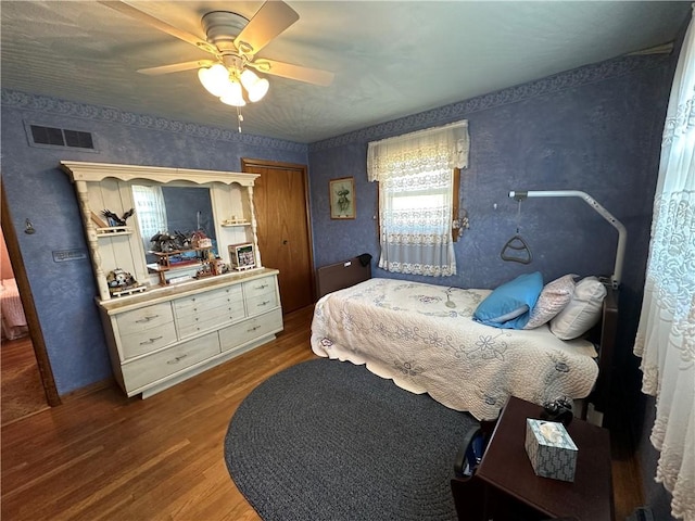 bedroom with a ceiling fan, wood finished floors, and visible vents