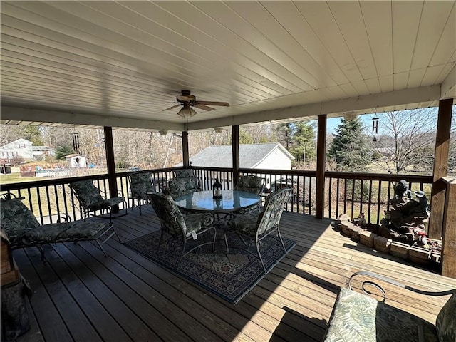 wooden terrace featuring outdoor dining area and a ceiling fan