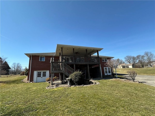 rear view of property with brick siding, a lawn, stairs, and ceiling fan