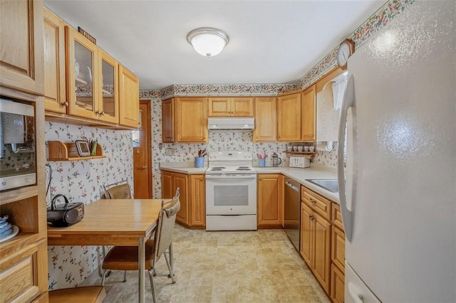 kitchen featuring under cabinet range hood, wallpapered walls, stainless steel appliances, light countertops, and glass insert cabinets