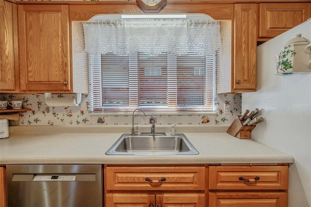 kitchen featuring stainless steel dishwasher, light countertops, and a sink