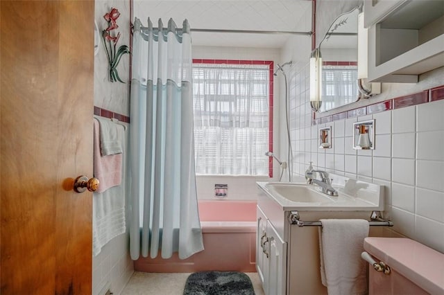 bathroom with a wealth of natural light, tile walls, vanity, and shower / bath combination with curtain