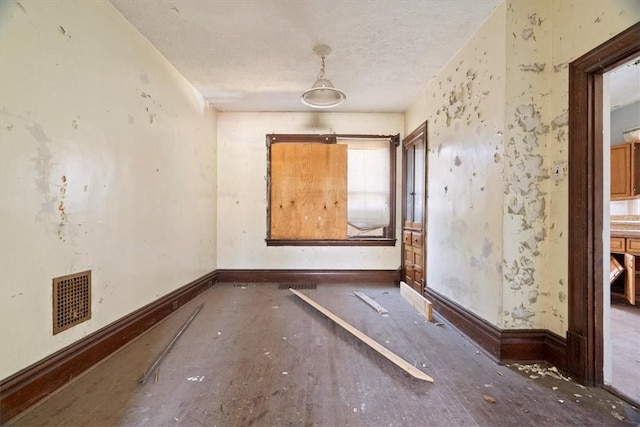 spare room featuring visible vents, baseboards, and a textured ceiling