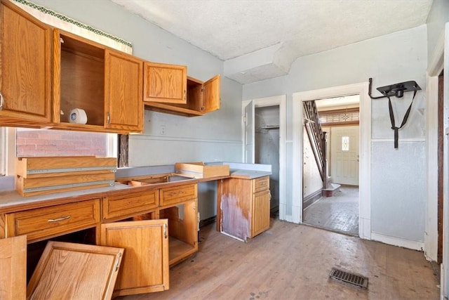 kitchen featuring visible vents, open shelves, light wood-style flooring, a textured ceiling, and brown cabinets